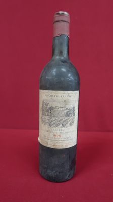 an old bottle of wine sitting on top of a red table