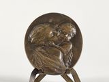 une image représentant une plaque en bronze sur laquelle figure une femme tenant un bébé dans ses bras