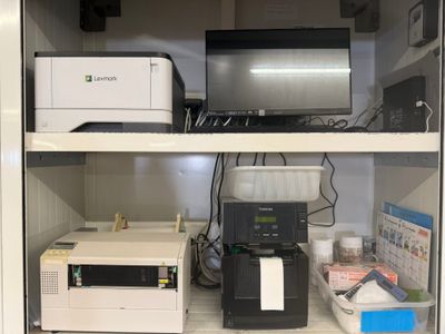 many different types of printers on the shelves in this cabinet