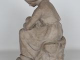 statue of a woman sitting on a rock with a hat on her head