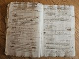 an old book sitting on top of a wooden table covered in writing
