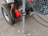a red and black lawn mower with a bucket on the back of it