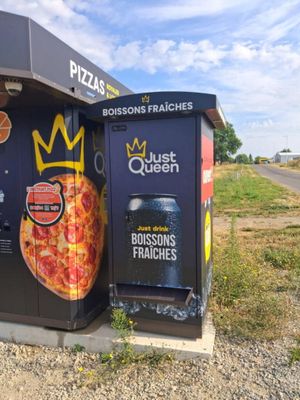 une boîte à pizza ornée d'une couronne, à côté d'une poubelle