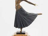 une image représentant une statue en bronze d'une femme en train de danser, posée sur un socle en bois