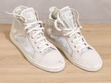 white high top sneakers with laces on a wooden surface