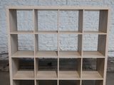 une photo d'une bibliothèque en bois devant un mur de briques blanches
