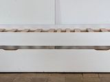 a white bed with two drawers underneath it on a wooden floor