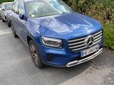 the blue mercedes suv is parked on the side of the road