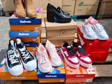 Plusieurs paires de chaussures sont empilées sur des cartons posés sur une palette