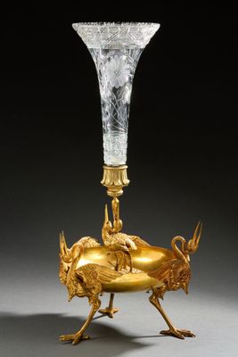 un vase en or orné d'un oiseau et surmonté d'un autre oiseau