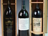 two bottles of red wine in a wooden box on a table