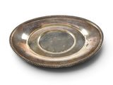 an antique silver plate with a beaded edge on a white surface