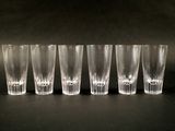 six verres à shot alignés sur une surface noire