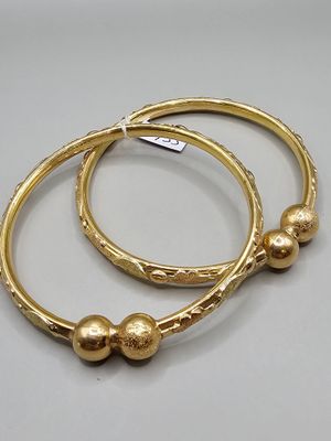 deux bracelets en or ornés de perles, posés sur un fond blanc