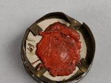 a close up of a red wax seal on a white surface