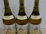 three bottles of wine are lined up on a tile floor
