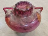 a pink vase sitting on a table with a red handle