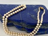 un gros plan d'un collier de perles blanches posé sur un rocher bleu