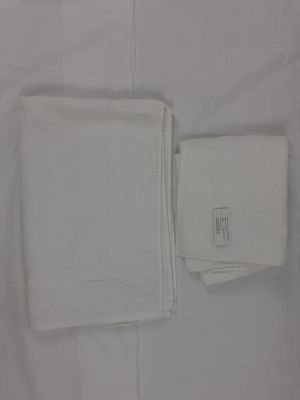 une serviette blanche et une serviette de table blanche posées sur un lit