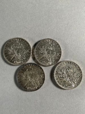 four silver coins sitting on top of each other on a white surface