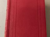 a red book sitting on top of a table next to a white table