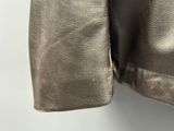 silver leather jacket hanging on a hanger against a white wall