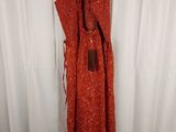 an orange dress hanging on a hanger in front of a white curtain