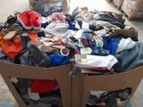 a cardboard box full of clothes and shoes on the floor