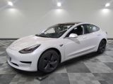 a white tesla model 3 parked on a checkered tile floor