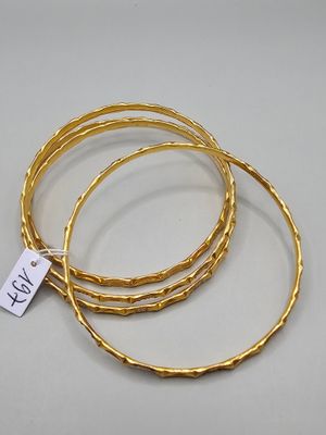 un lot de trois bracelets rigides en or avec une étiquette