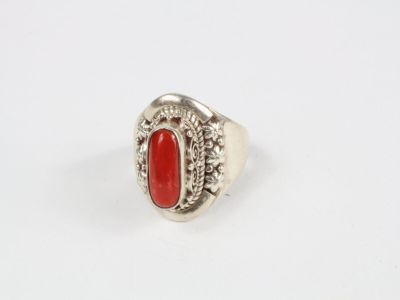 un gros plan d'une bague en argent sertie d'une pierre rouge