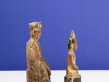 pair of wooden statues of a man and a woman sitting on a bench