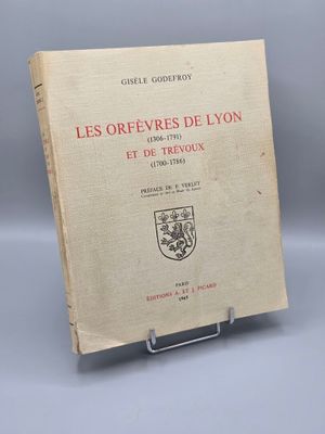 un vieux livre posé sur un support métallique, sur une surface grise