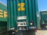 two green semi trucks parked next to each other on the side of the road