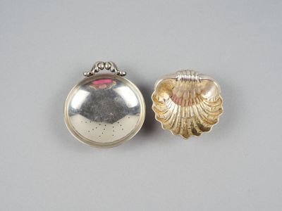 une paire de cuillères en argent ornées de coquillages, posées sur une table