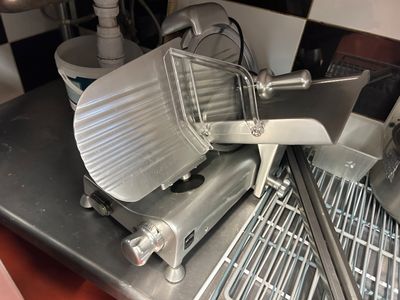 une photo d'une trancheuse à viande professionnelle posée sur un plan de travail