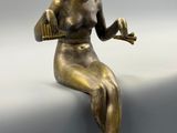 statue en bronze représentant une femme assise sur un rebord, tenant un oiseau dans ses mains
