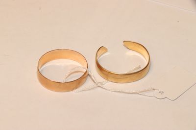deux bagues en or posées sur une surface blanche, à côté d'une paire de ciseaux