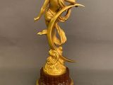 bronze figurine of a mermaid holding a fish on a marble base