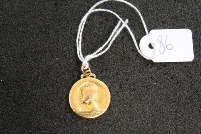 une médaille d'or suspendue à un cordon, avec une étiquette indiquant son prix