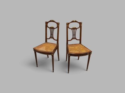une paire de chaises anciennes avec des dossiers en rotin sur fond gris