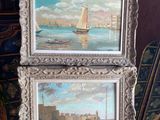 two framed paintings of boats on a table with a chair in the background