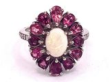 an image of a ring with a white oplite surrounded by pink sapphires