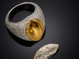 a close up of a ring with a yellow stone and a diamond