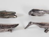 three silver figurines of birds on a white surface