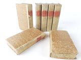 several old books are stacked on top of each other on a white surface