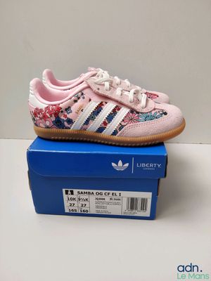 une paire de chaussures Adidas roses posée sur une boîte bleue