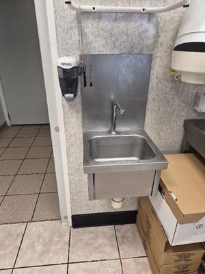 un lavabo dans des toilettes publiques, avec des cartons par terre
