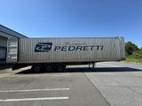 Le camion est garé devant un immeuble, avec le ciel bleu en arrière-plan.