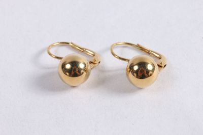 a pair of gold ball earrings on a white surface